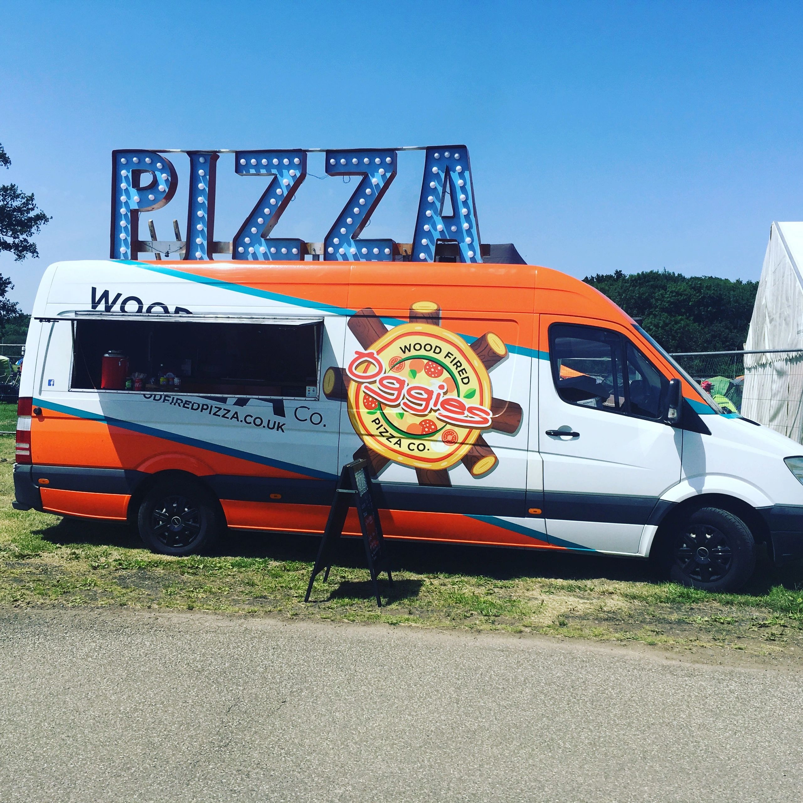 Oggies orange mobile pizza van at an outdoor event